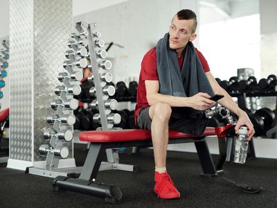 Water bottle and towel on a bench in gym.